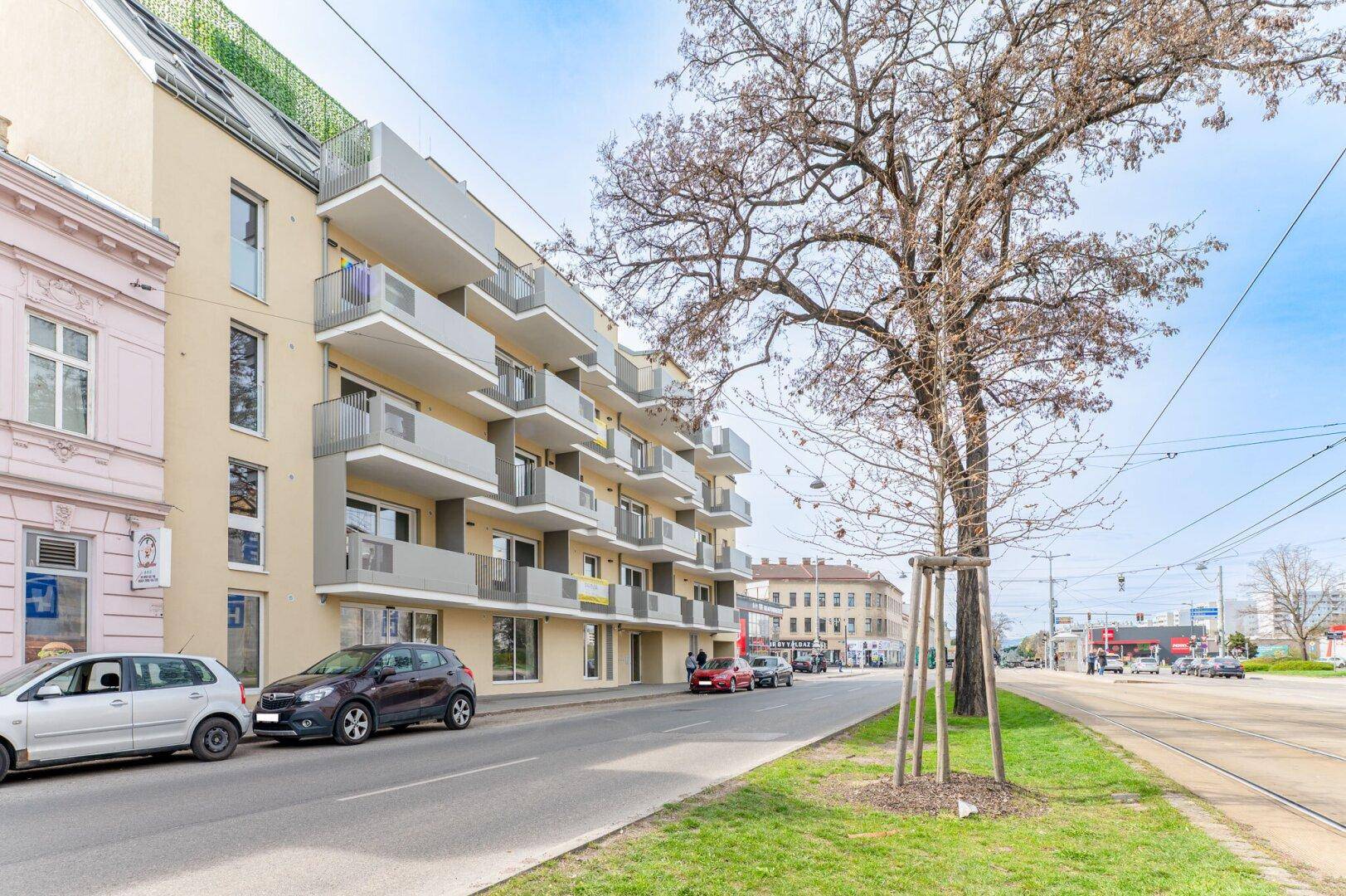 Attraktives Mehrfamilienhaus mit Balkonen und großen Fenstern an einer belebten Straße.