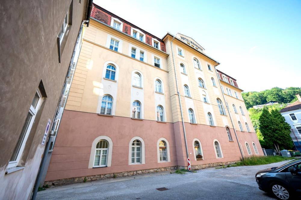 Seitenansicht des historischen Gebäudes mit Parkplatz und angrenzendem Gebäude.