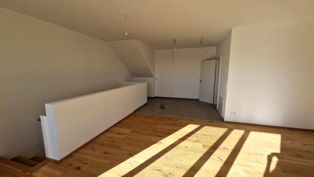 Geräumiger Innenraum mit Holzboden und weiß gestrichenen Wänden, bereit für die Einrichtung.