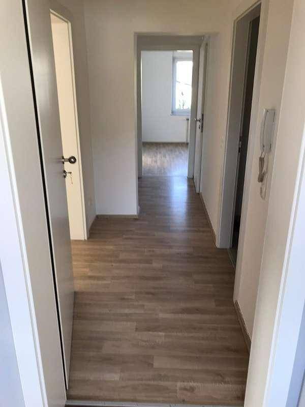 Heller Flur mit modernem Laminatboden und weißen Wänden, der zu weiteren Räumen führt.