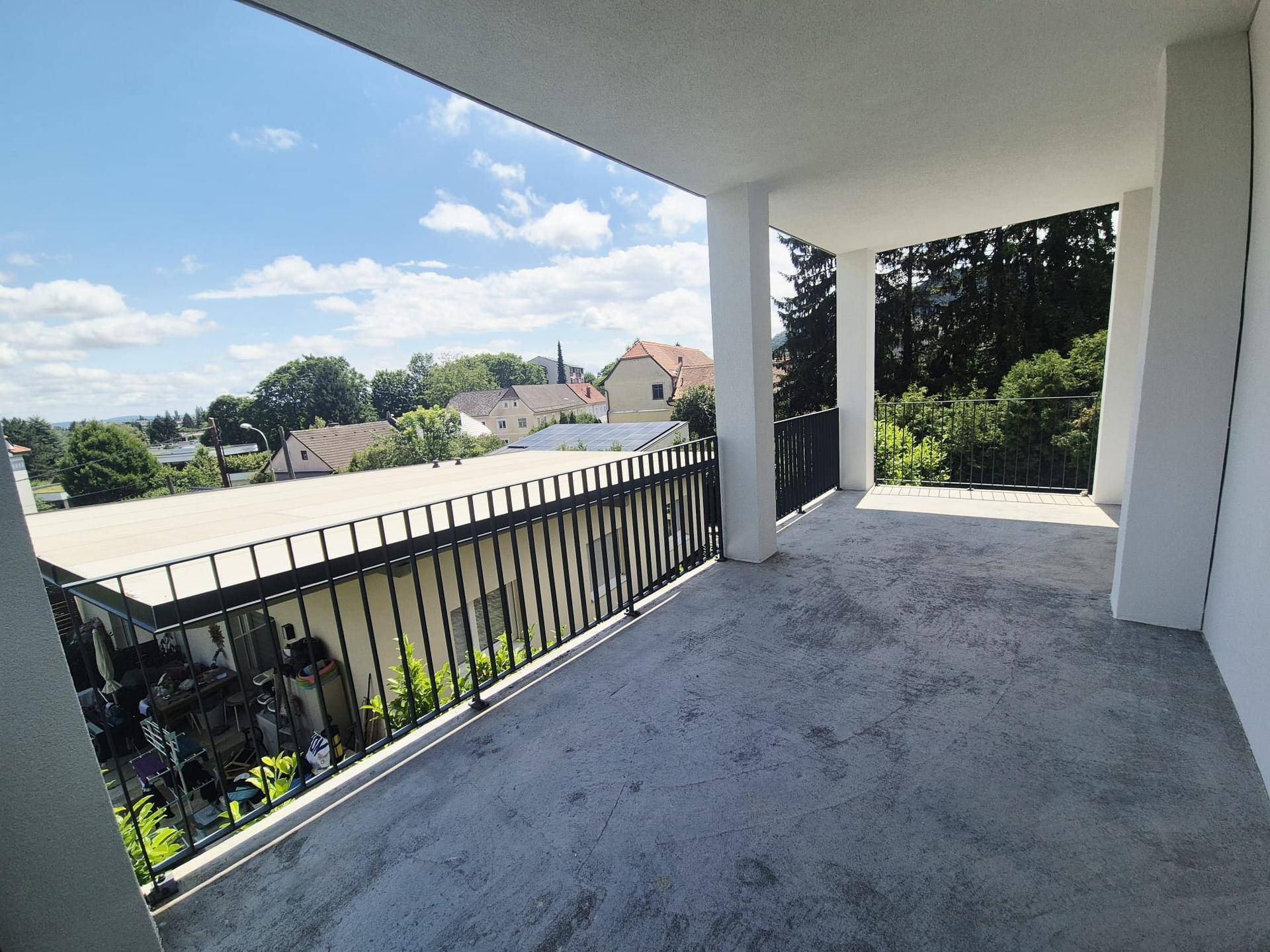 Geräumige überdachte Terrasse mit Blick auf die umliegende Wohngegend und grüne Bäume.
