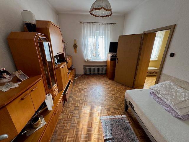 Gemütliches Schlafzimmer mit Parkettboden, Holzmöbeln und einem Einzelbett, gut beleuchtet durch ein Fenster.
