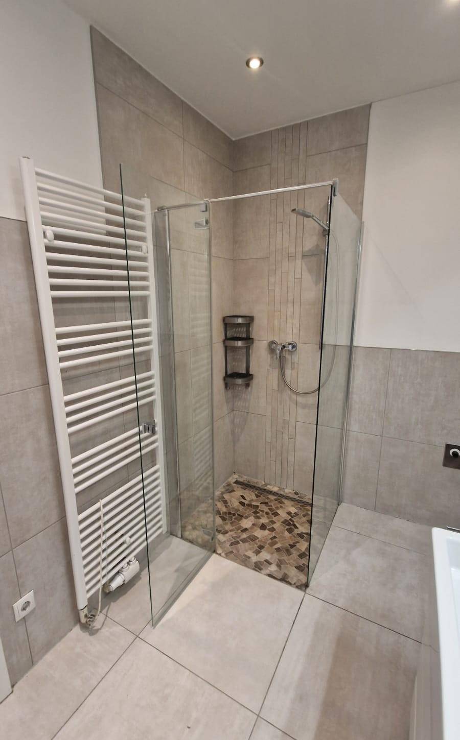 Geräumige Duschkabine mit Glaswänden und Mosaikboden im modernen Badezimmer.