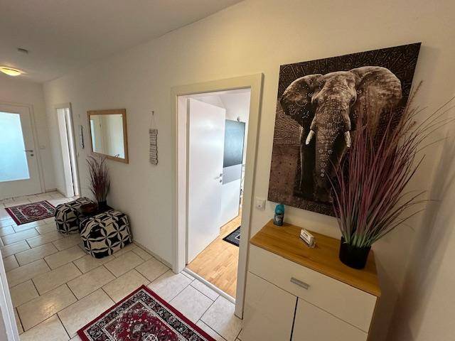 Geräumiger Flur mit Fliesenboden, Elefantenbild und Zugang zu weiteren Räumen.
