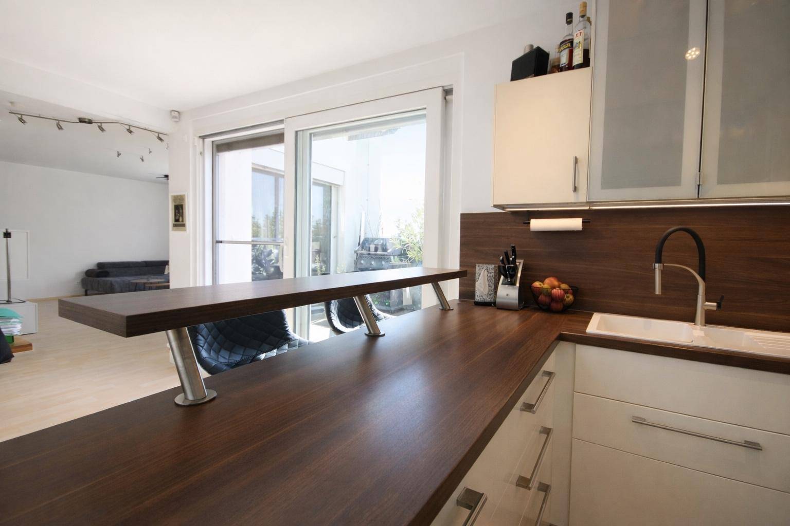 Offene Küche mit Frühstücksbar und direktem Zugang zum Wohnbereich und zur Terrasse.