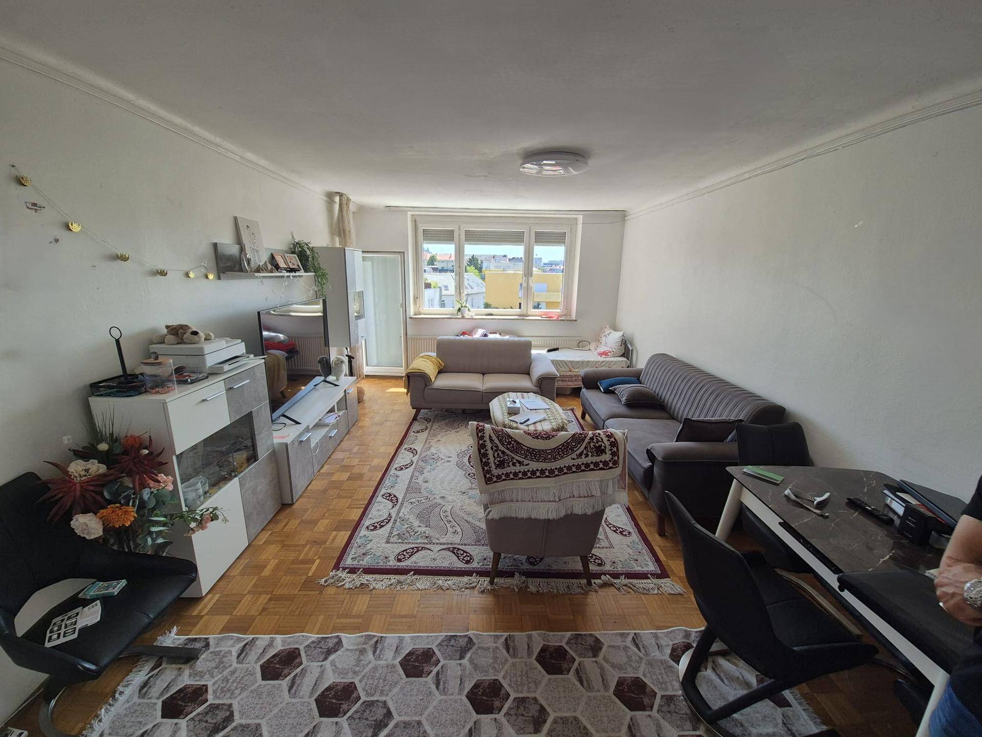 Helles Wohnzimmer mit Parkettboden, gemütlicher Einrichtung und Blick ins Grüne.