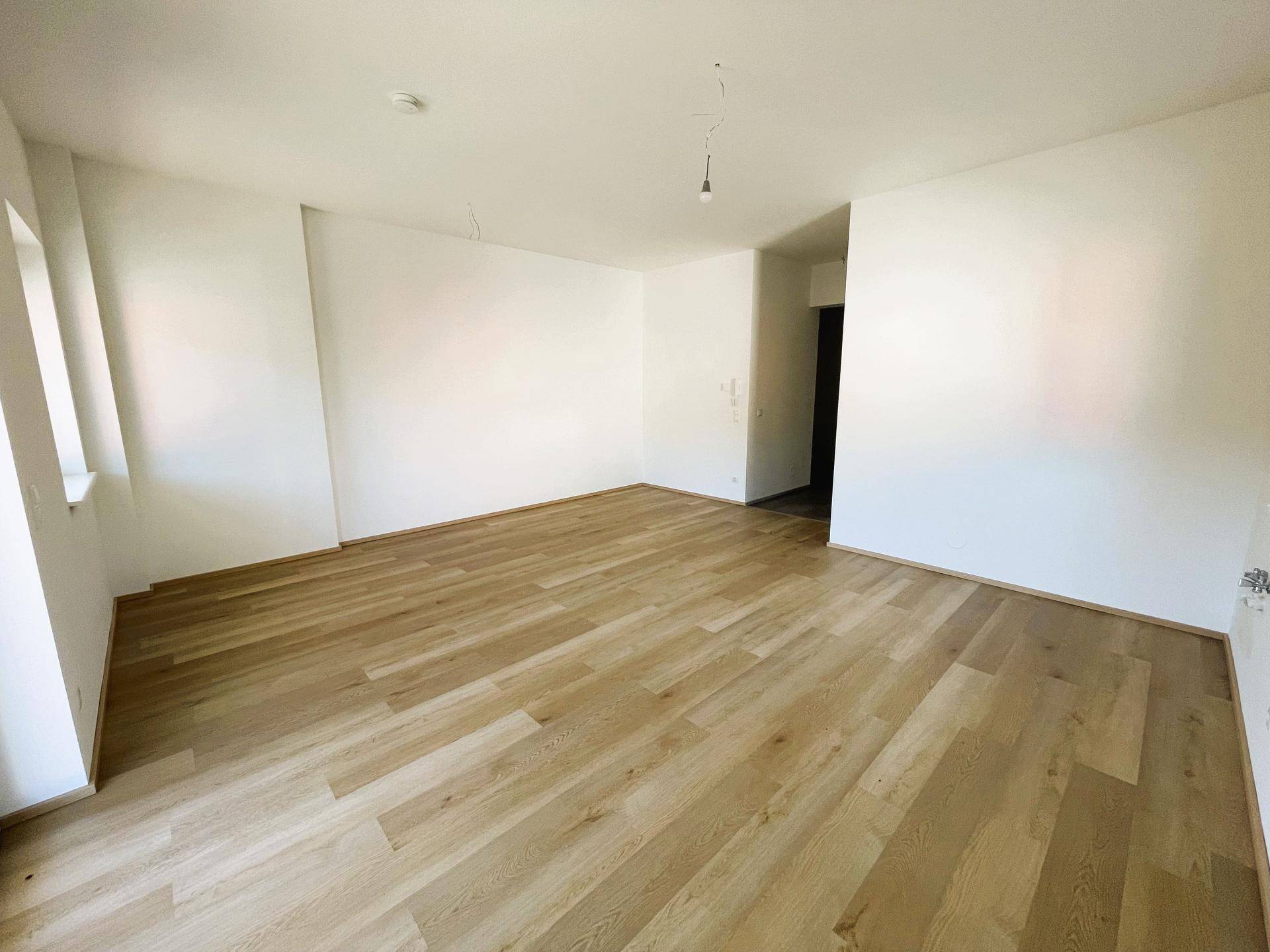 Heller Wohnbereich mit Laminatboden und großen Fenstern, die viel Licht spenden.