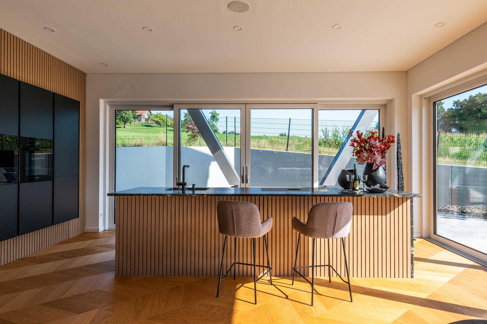 Stilvolle Kücheninsel mit integrierter Spüle und Blick auf die grüne Umgebung.