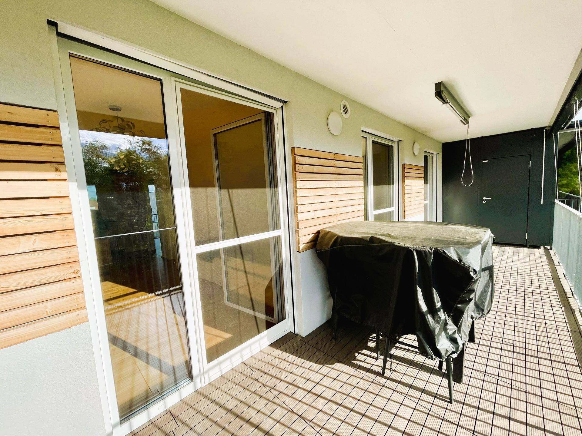 Geräumiger Balkon mit Holzboden und Sitzgelegenheiten, ideal für entspannte Stunden im Freien.