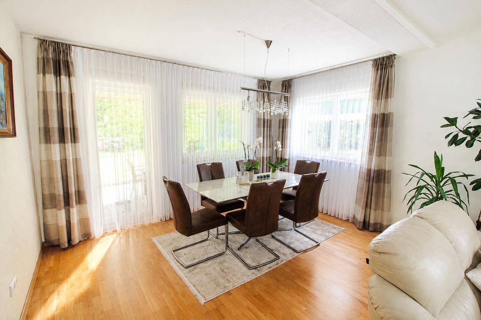 Heller Essbereich mit großem Tisch, bequemen Stühlen und Zugang zum Garten.