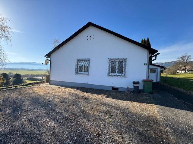 Seitenansicht des weißen Hauses mit Fenstern und Blick auf die umliegende Landschaft.
