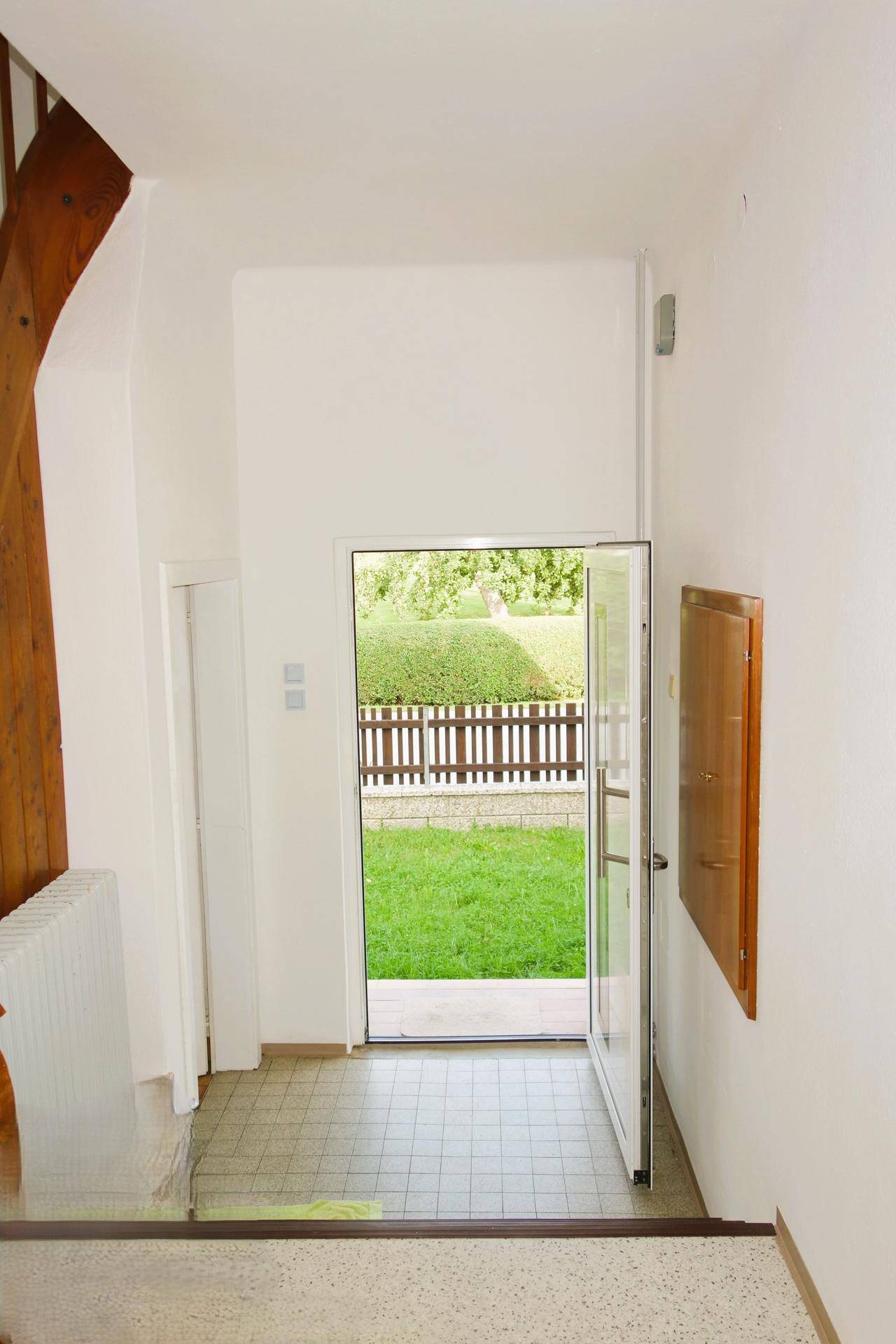 Heller Eingangsbereich mit Fliesenboden und direktem Blick sowie Zugang zum Garten.