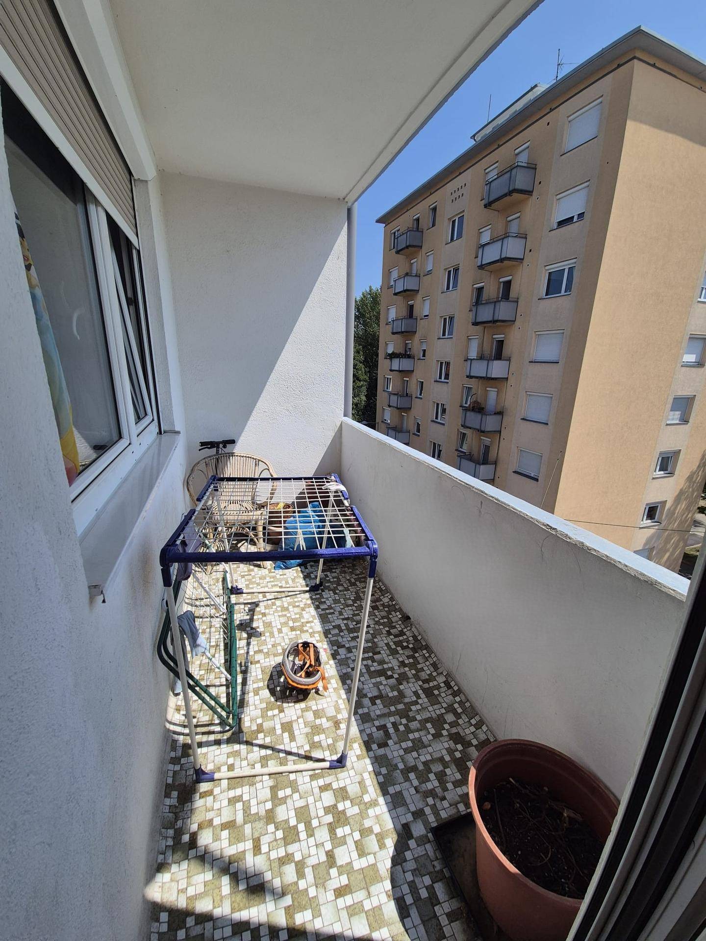 Schmaler Balkon mit Fliesenboden und Blick auf umliegende Gebäude.