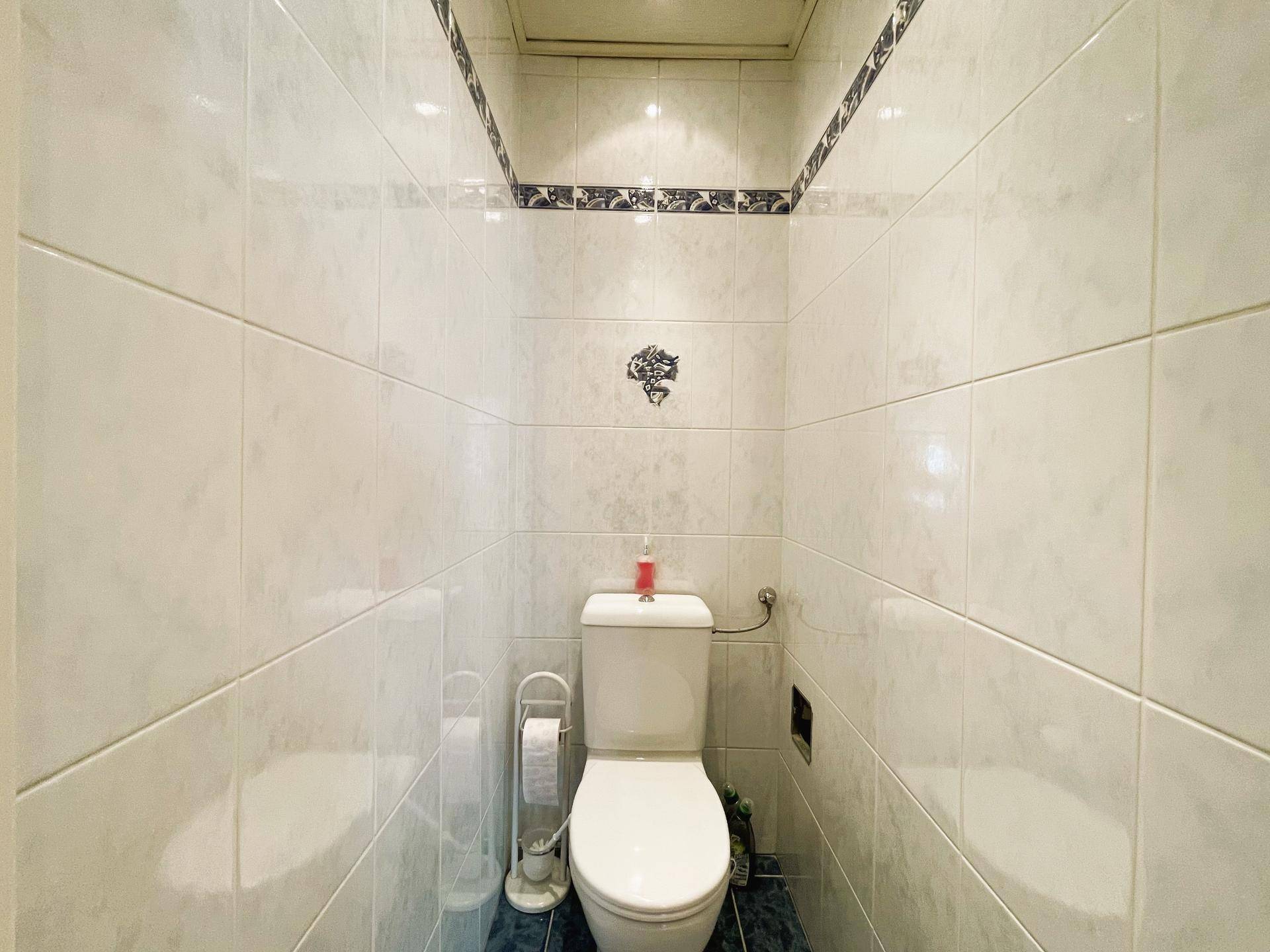 Kleines separates WC mit weißen Fliesen und blauen Akzenten.