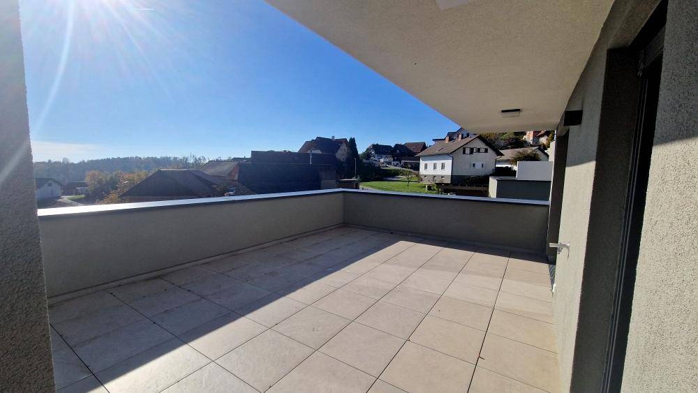 Sonnige Außenterrasse mit modernen Fliesen und einem Panoramablick auf die weite Umgebung.