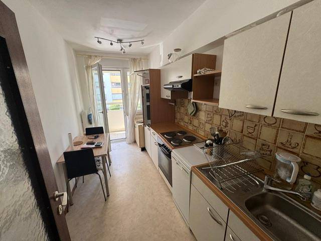 Kleine Einbauküche mit Essbereich und direktem Zugang zum Balkon.