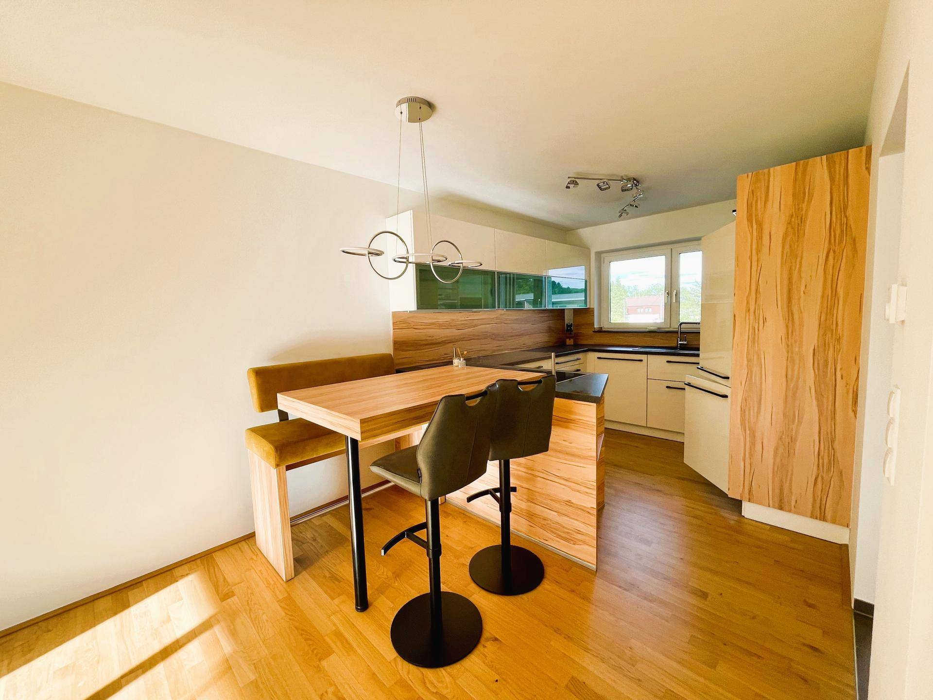 Helle, moderne Küche mit Holzelementen, Frühstücksbar und integriertem Essbereich.