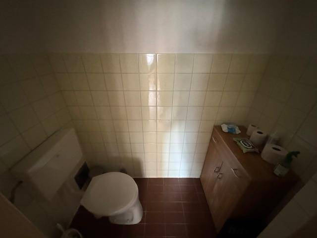 Kleines Gäste-WC mit Toilette, Waschbecken und hellen Wandfliesen.