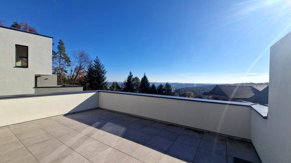 Weitläufige Dachterrasse mit Fliesenboden und einem beeindruckenden Panoramablick über die Landschaft.