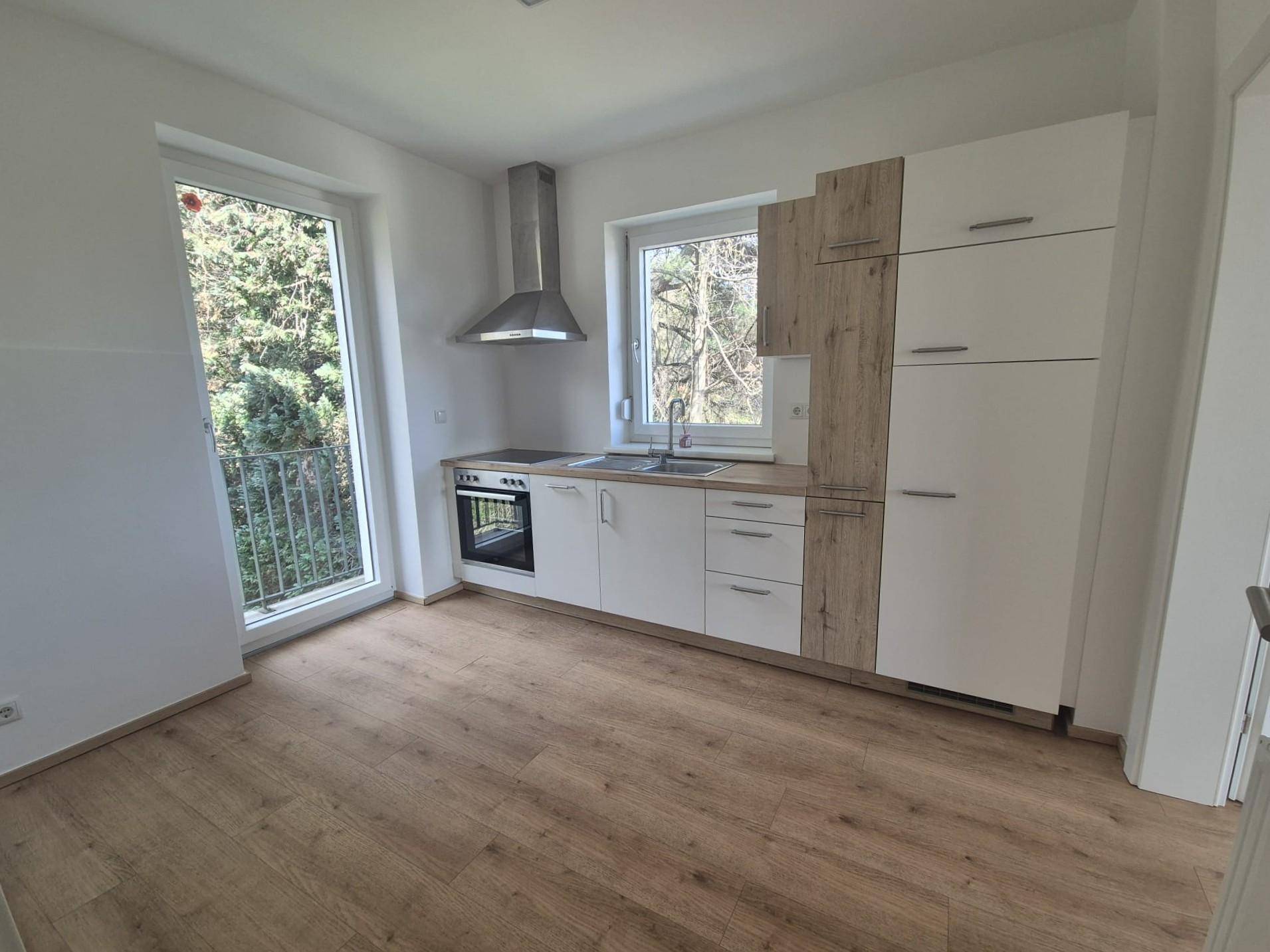 Moderne Einbauküche mit weißen und holzfarbenen Fronten, ausgestattet mit Backofen und Dunstabzugshaube.