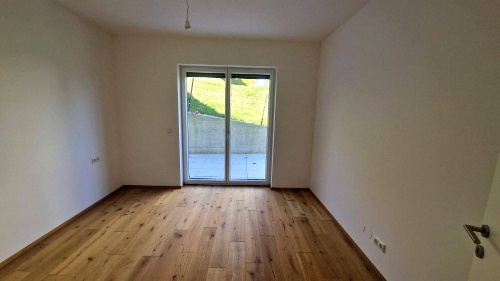 Schlafzimmer mit Holzboden und direktem Zugang zu einer kleinen Terrasse im Grünen.