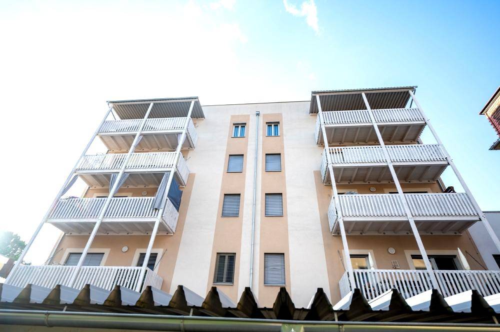 Fassade eines modernen Wohngebäudes mit mehreren Balkonen und überdachtem Bereich.