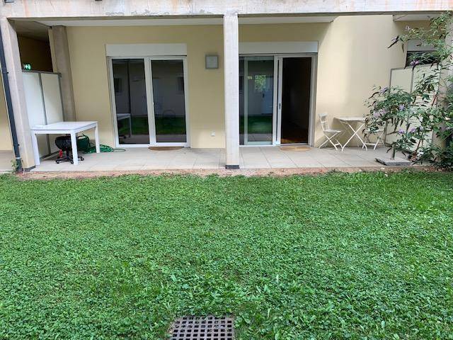 Grüne Gartenfläche mit angrenzender Terrasse und Zugang zu den Wohnräumen.