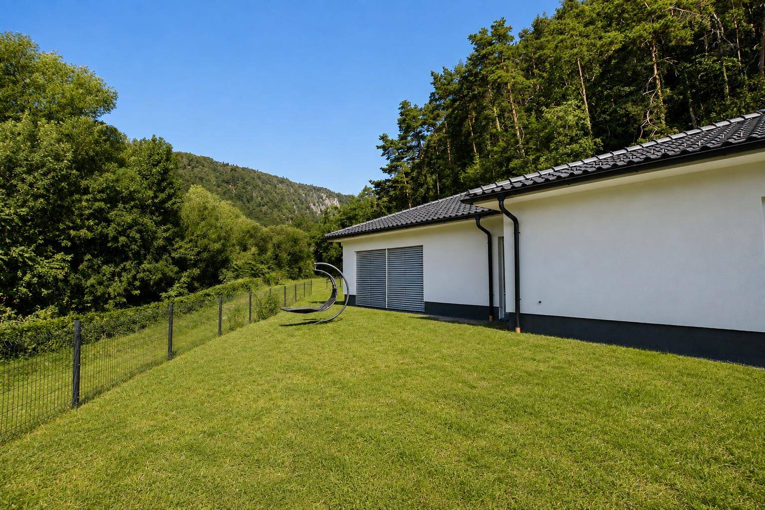 Ansicht des Bungalows mit Garten und Blick auf die bewaldeten Hügel in der Ferne.