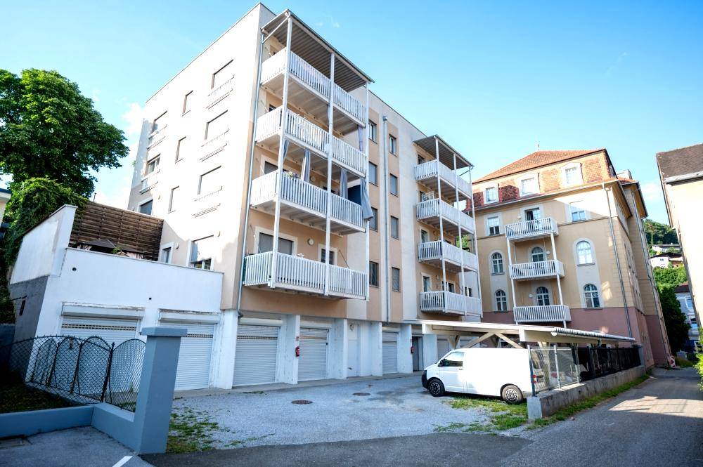 Modernes Wohngebäude mit Balkonen, Garagen und überdachten Parkplätzen.