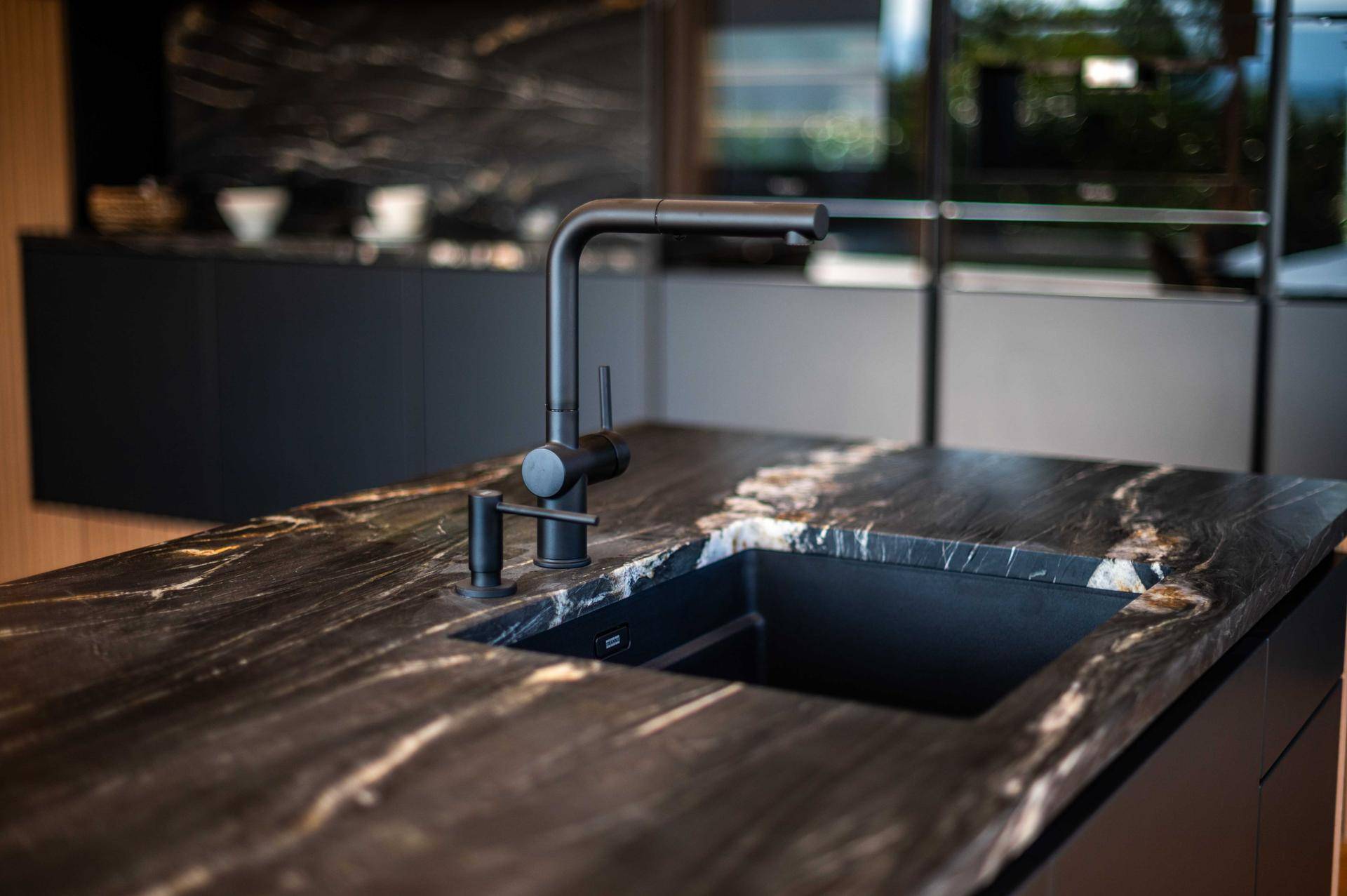 Moderne schwarze Spüle mit passendem Wasserhahn in der Kücheninsel.