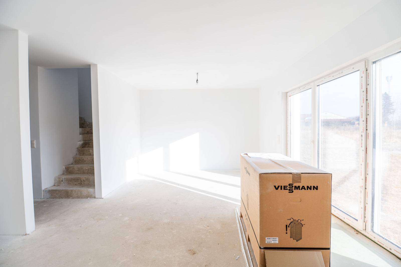 Geräumiger Wohnbereich im Rohbau mit viel Tageslicht und einer Viessmann-Verpackung.