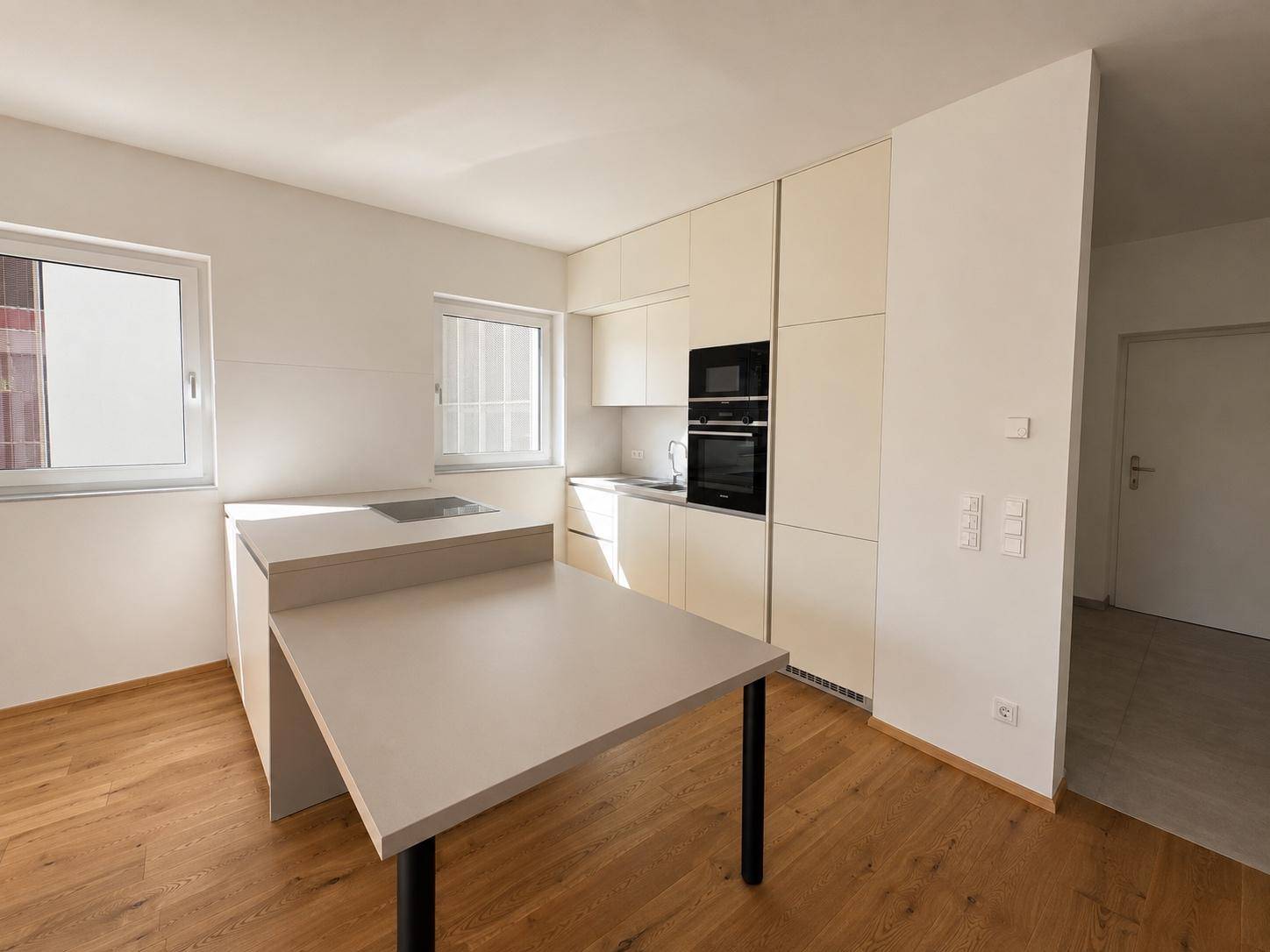 Moderne Küche mit hellen Einbauschränken, integrierten Geräten und Holzboden.