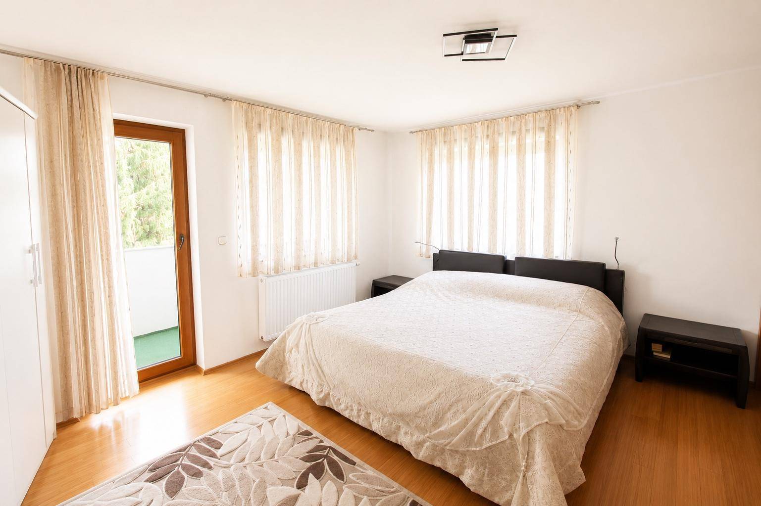 Geräumiges Schlafzimmer mit Doppelbett, Holzboden und direktem Zugang zum Balkon.