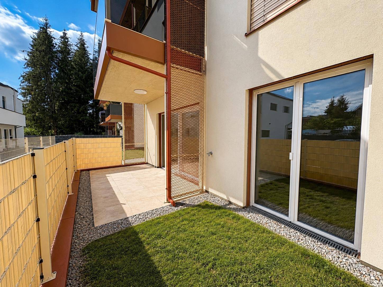Kleiner privater Gartenbereich mit Rasenfläche, Kies und angrenzender Terrasse.