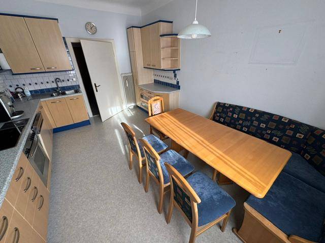 Helle Wohnküche mit Essecke, Holztisch und blauen Stühlen, ideal für Familienmahlzeiten.