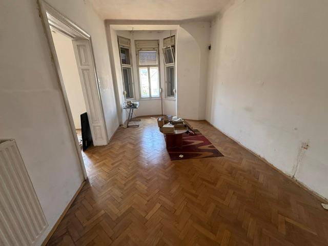 Wohnzimmer mit Fischgrätparkett und Erkerfenster, renovierungsbedürftig.