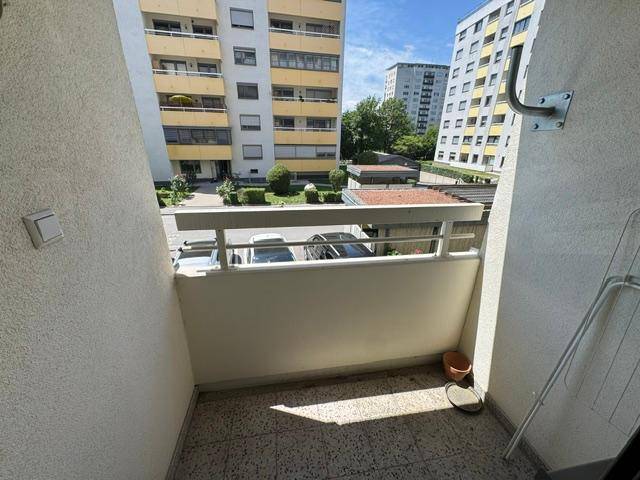 Sonnenverwöhnter Balkon mit Fliesenboden und Blick auf die umliegenden Gebäude.