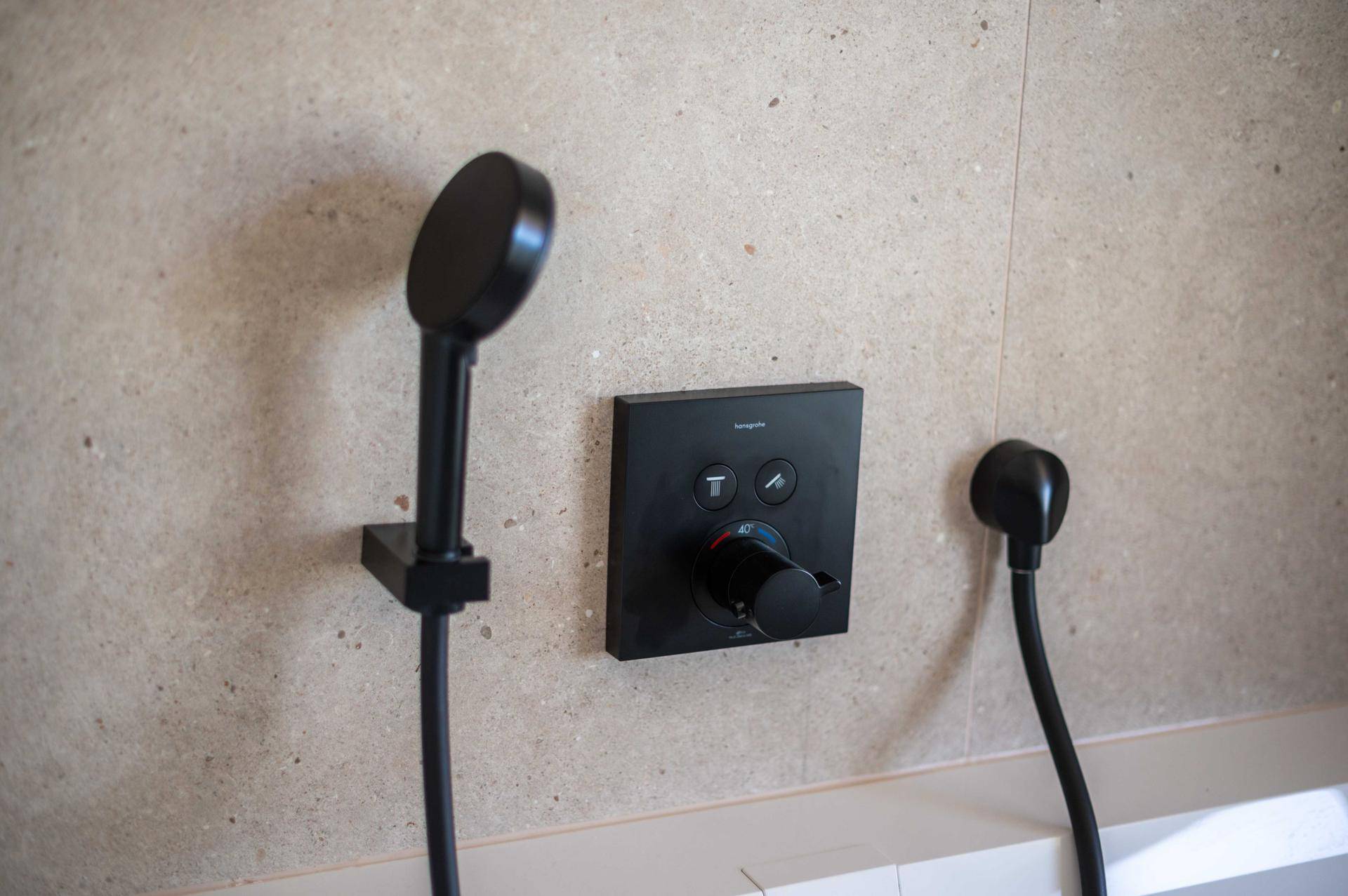 Moderne schwarze Duscharmatur mit Handbrause in der begehbaren Dusche.