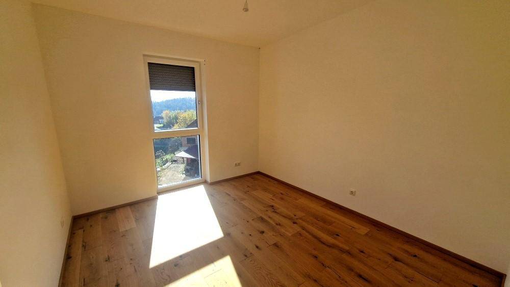 Helles Schlafzimmer mit Holzboden und großem Fenster, ausgestattet mit einem Rollladen für Privatsphäre.