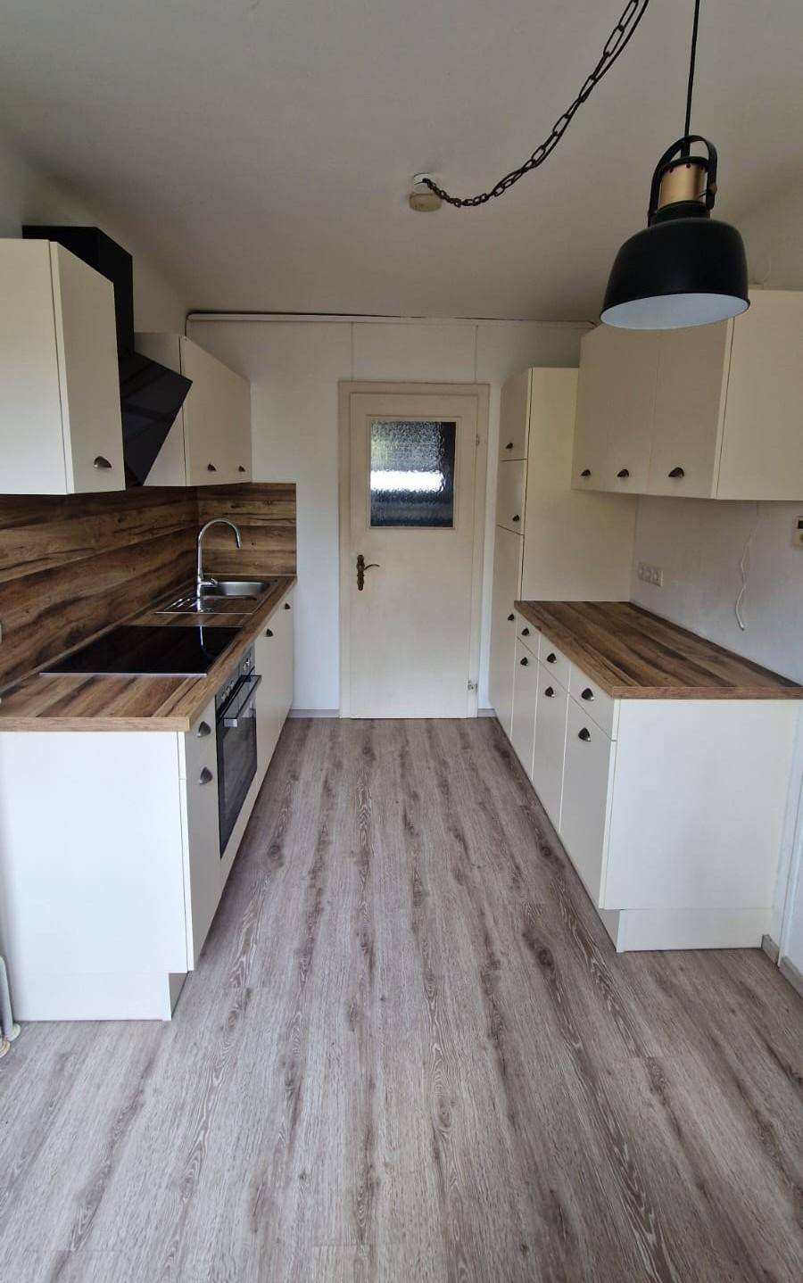 Moderne Küche mit weißen Schränken, Holz-Arbeitsplatten und integrierten Geräten.