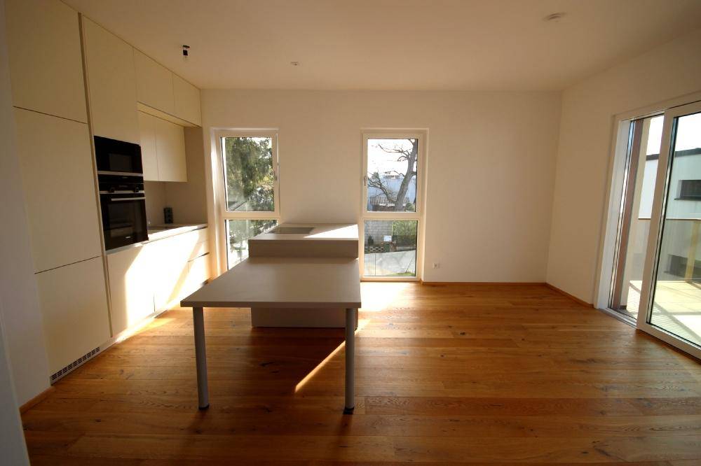 Moderne Einbauküche mit hellen Fronten, Holzboden und viel Tageslicht.