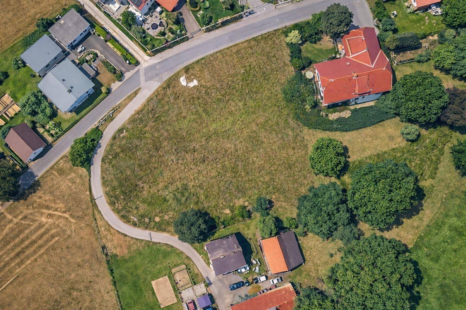 Luftaufnahme eines unbebauten Grundstücks, umgeben von Straßen und Wohngebäuden in ländlicher Umgebung.