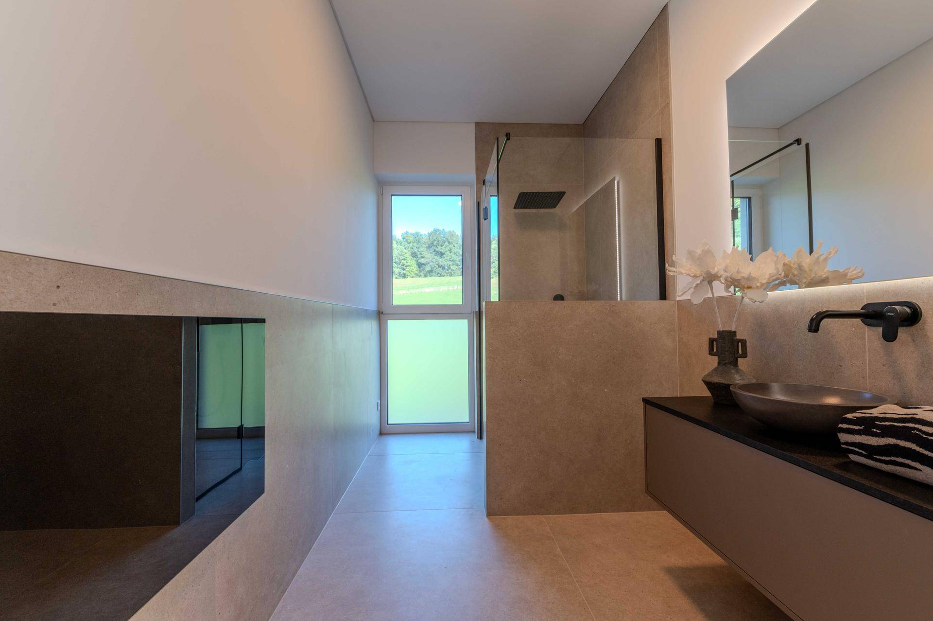 Modernes Badezimmer mit begehbarer Dusche, Waschtisch und Fenster.