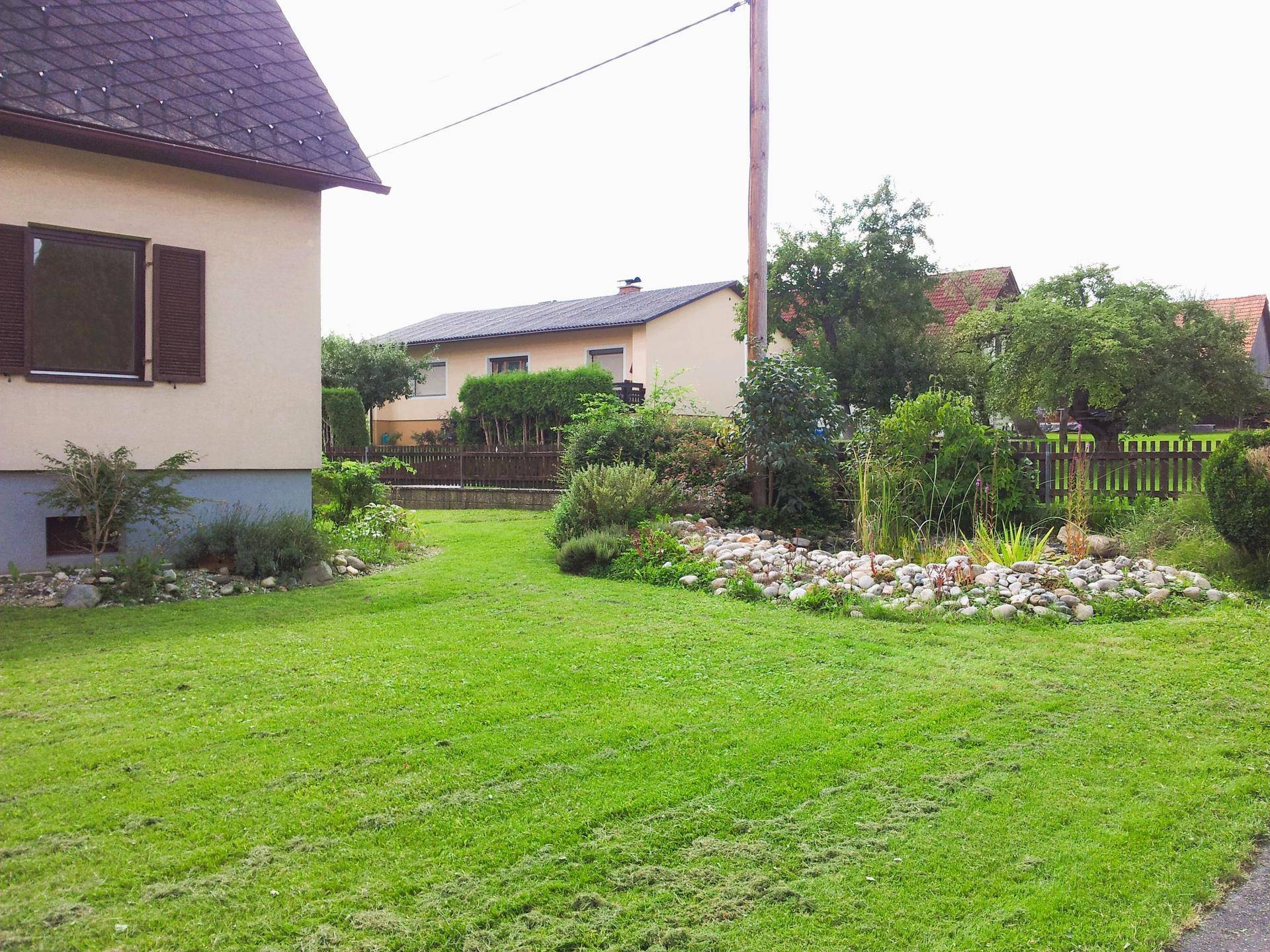 Gartenbereich mit einem dekorativen Steingarten und einer weitläufigen Rasenfläche.