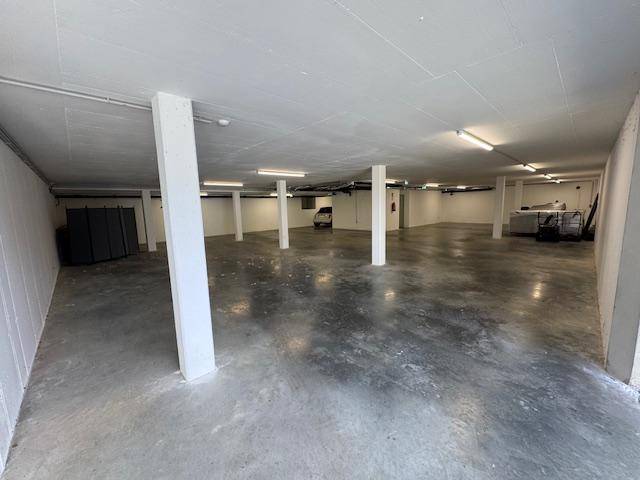 Geräumige Tiefgarage mit Betonboden und Säulen, bietet viel Platz für Fahrzeuge.
