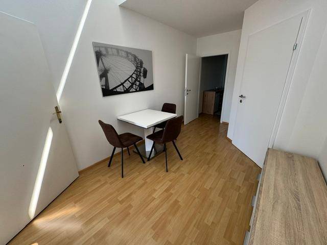 Kleiner Essbereich mit Holzboden, weißem Tisch und dunklen Stühlen, hell und funktional.