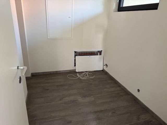 Unfertiger Raum mit Laminatboden, Fenster und sichtbaren Elektroinstallationen, bereit für den Ausbau.