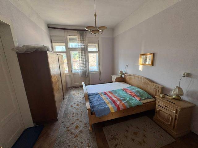 Schlafzimmer mit Holzbetten, Kleiderschrank und Nachttischen, ausgestattet mit einem Teppich und Tageslicht.
