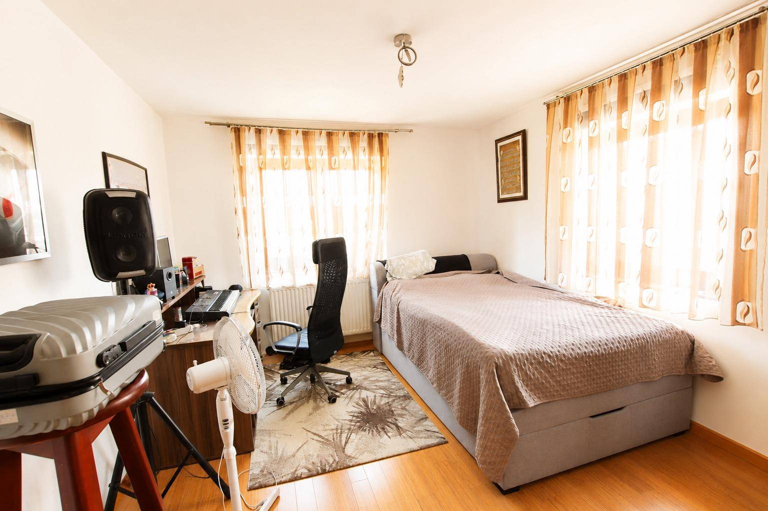 Helles Schlafzimmer, das auch als Büro genutzt wird, mit Bett, Schreibtisch und Computer.