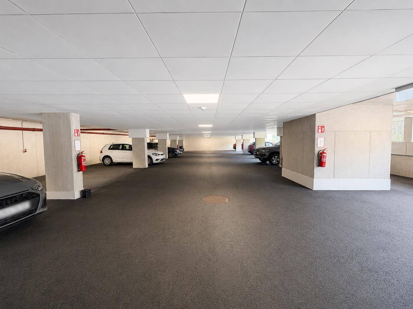 Tiefgarage mit mehreren Stellplätzen und Brandschutzvorrichtungen.